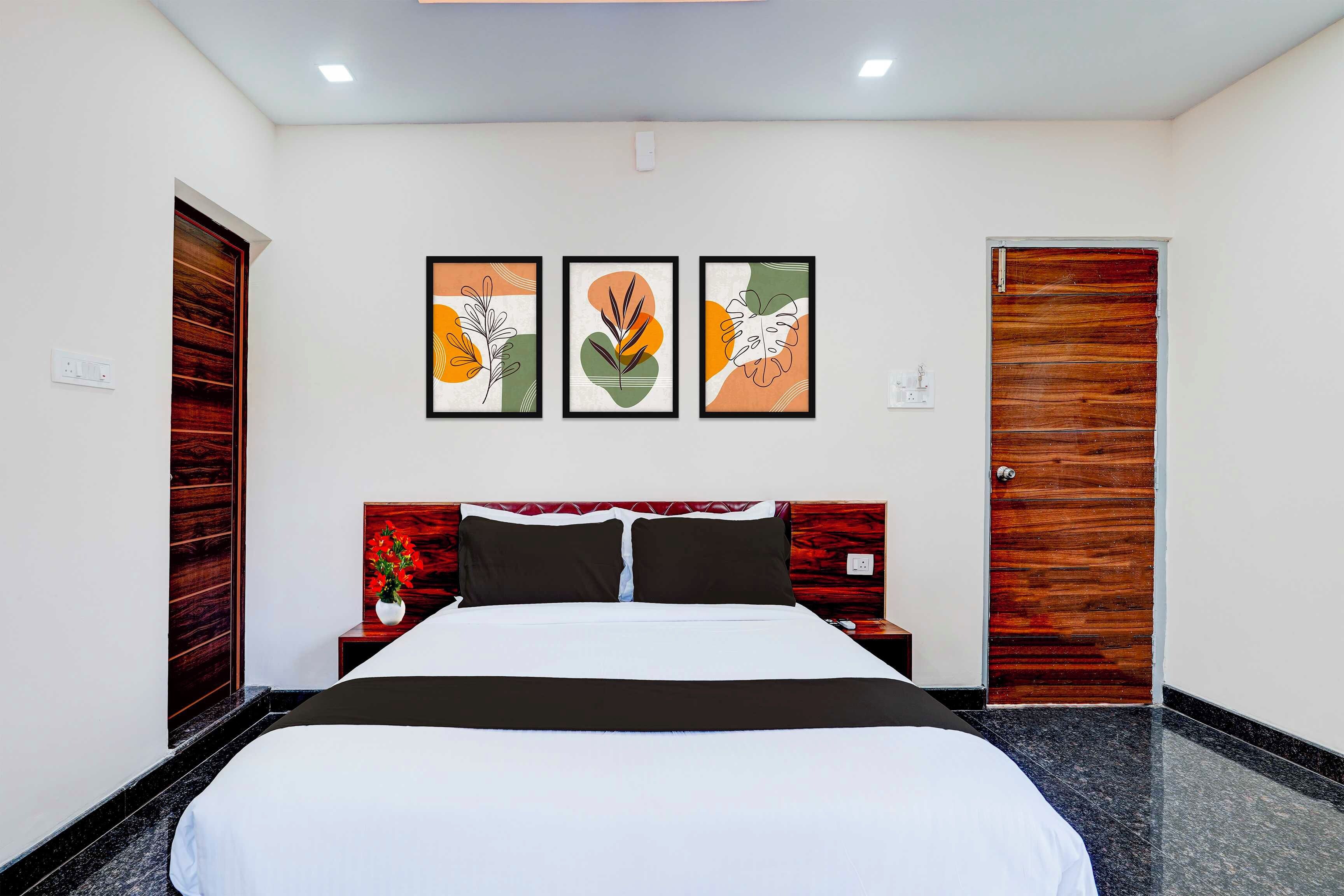 A hotel room with a bed, a nightstand, a wall-mounted power outlet, and a door.