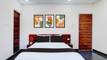 A hotel room with a bed, a nightstand, a wall-mounted power outlet, and a door.