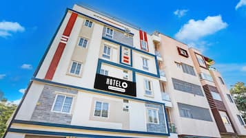 A multi-story hotel building with a prominent 'HOTEL' sign, multiple balconies, and a mix of window styles.