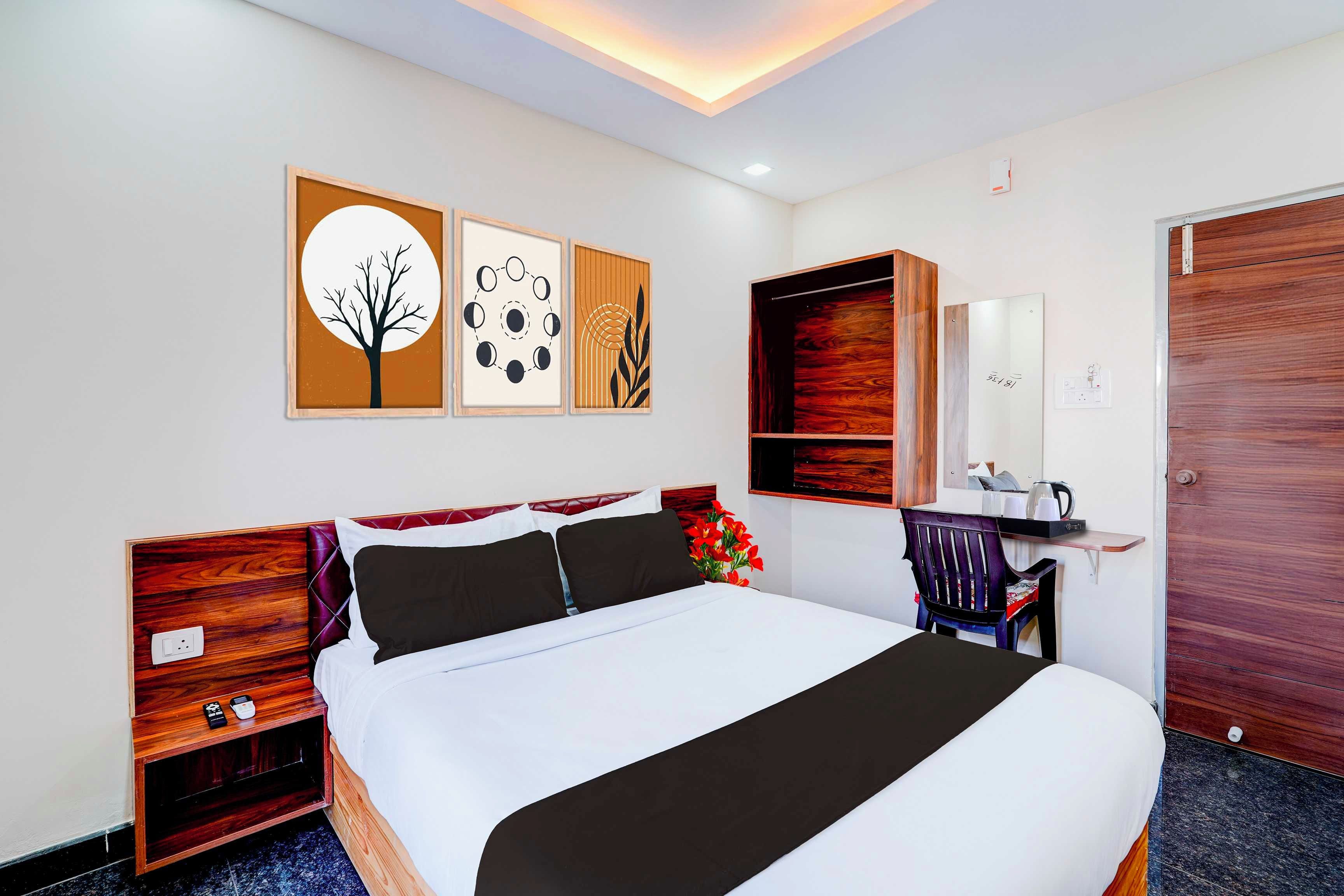 A hotel room with a bed, bedside tables, a desk, a chair, a mirror, and artwork on the wall.