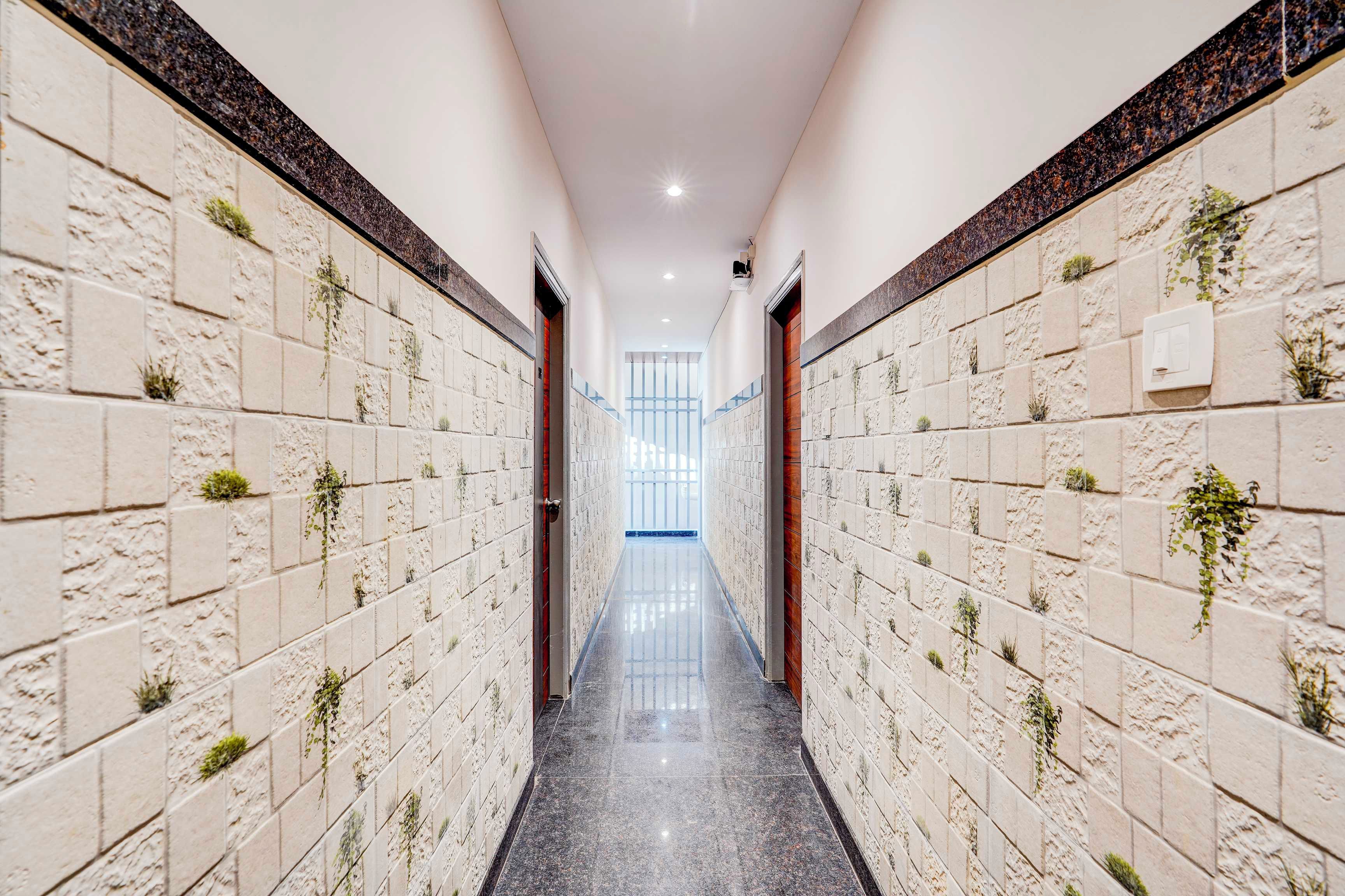 A corridor with tiled walls and a polished floor, leading to a bright room with a view.
