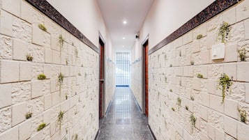 A corridor with tiled walls and a polished floor, leading to a bright room with a view.