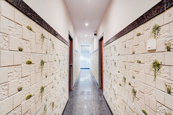 A corridor with tiled walls and a polished floor, leading to a bright room with a view.