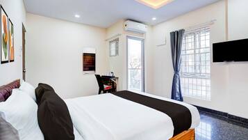 A hotel room with a bed, a desk, a chair, a television, and a window with curtains.