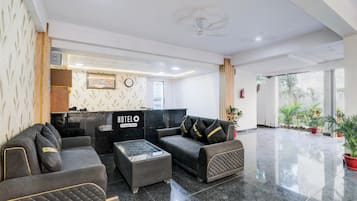 Un hall de hotel con mostrador de recepción, zona de estar y vistas al exterior.
