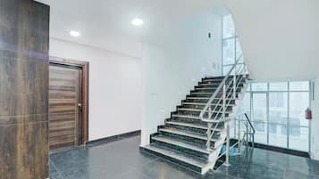 Un interior moderno con una escalera de mármol, una puerta de madera y una pared de vidrio.