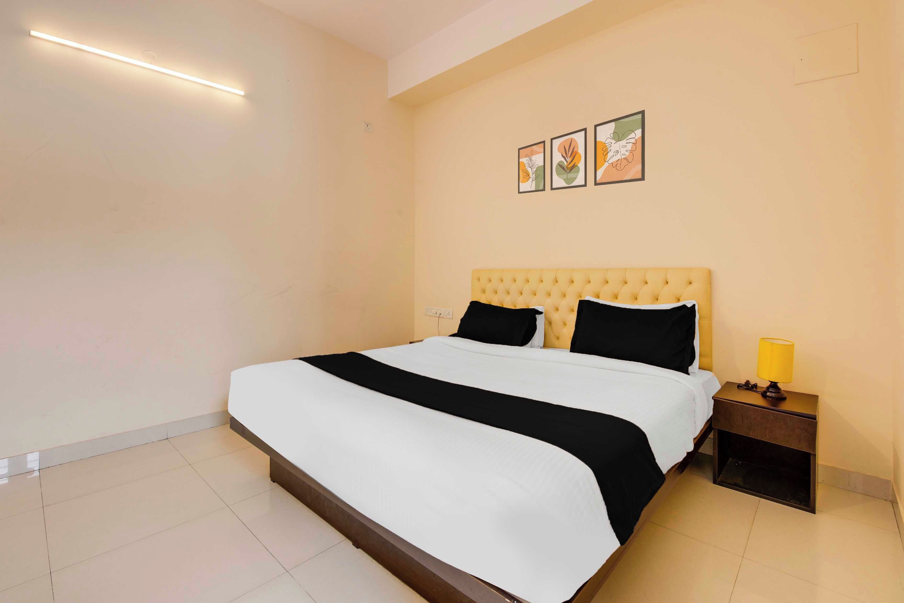 Habitación de hotel con una cama grande, una mesita de noche con lámpara y tres cuadros en la pared.