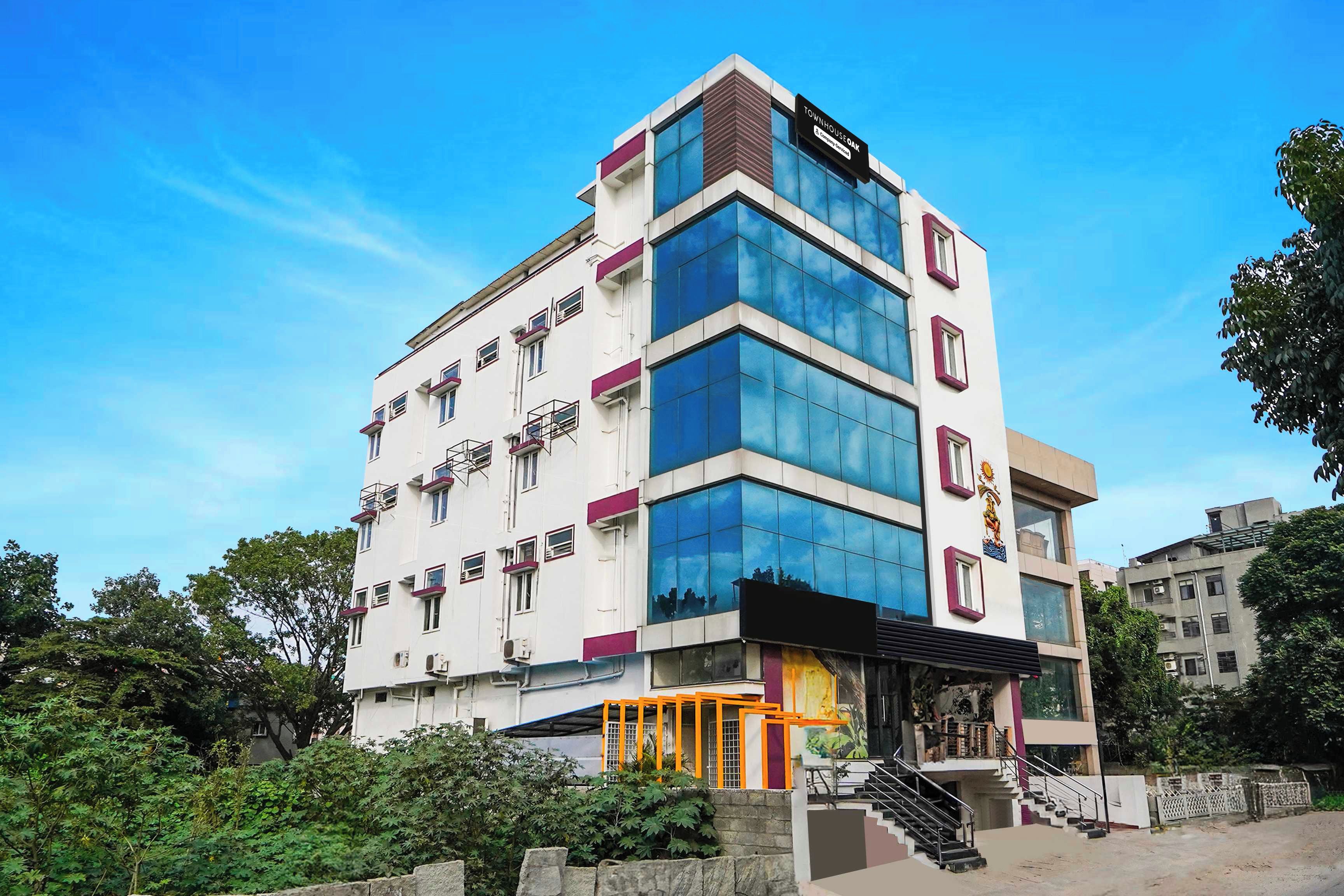 A multi-story building with a modern architectural design, featuring a mix of glass and concrete facades, and a prominent sign indicating it is a company service building.
