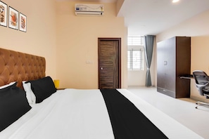 Habitación de hotel con cama, armario, escritorio con silla y ventana con cortinas.