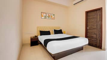 A hotel room with a bed, bedside table, wall art, and a wooden door.
