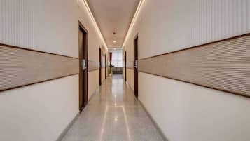 A hotel corridor with a polished floor, wooden paneling on the walls, and doors leading to rooms.
