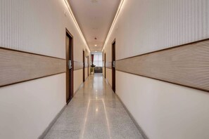 A hotel corridor with a polished floor, wooden paneling on the walls, and doors leading to rooms. - Townhouse Oak HBR Layout (Bengaluru)