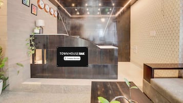 A reception area with a black reception desk, clocks on the wall, and a sign indicating the property is company-serviced.