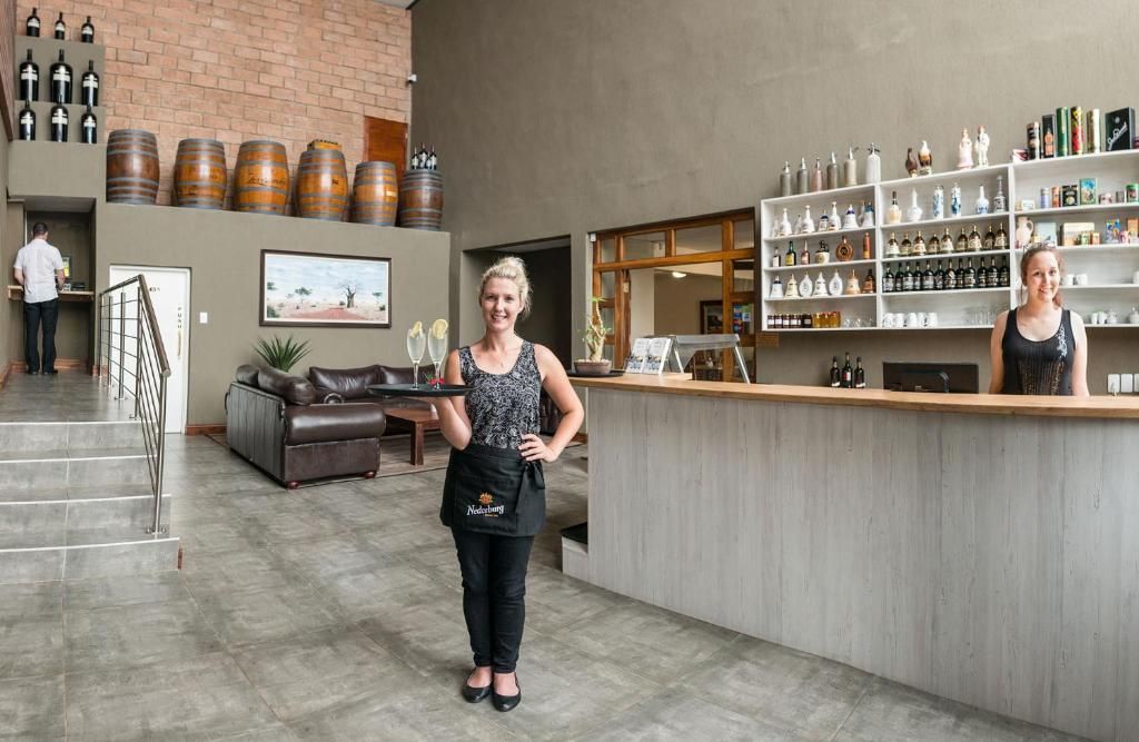A bar area with a counter, shelves with bottles, and a staircase leading to another level.