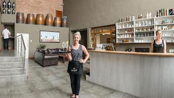 A bar area with a counter, shelves with bottles, and a staircase leading to another level.