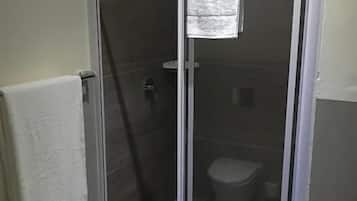 Una doccia con porta in vetro, un asciugamano appeso alla porta e un pavimento piastrellato.