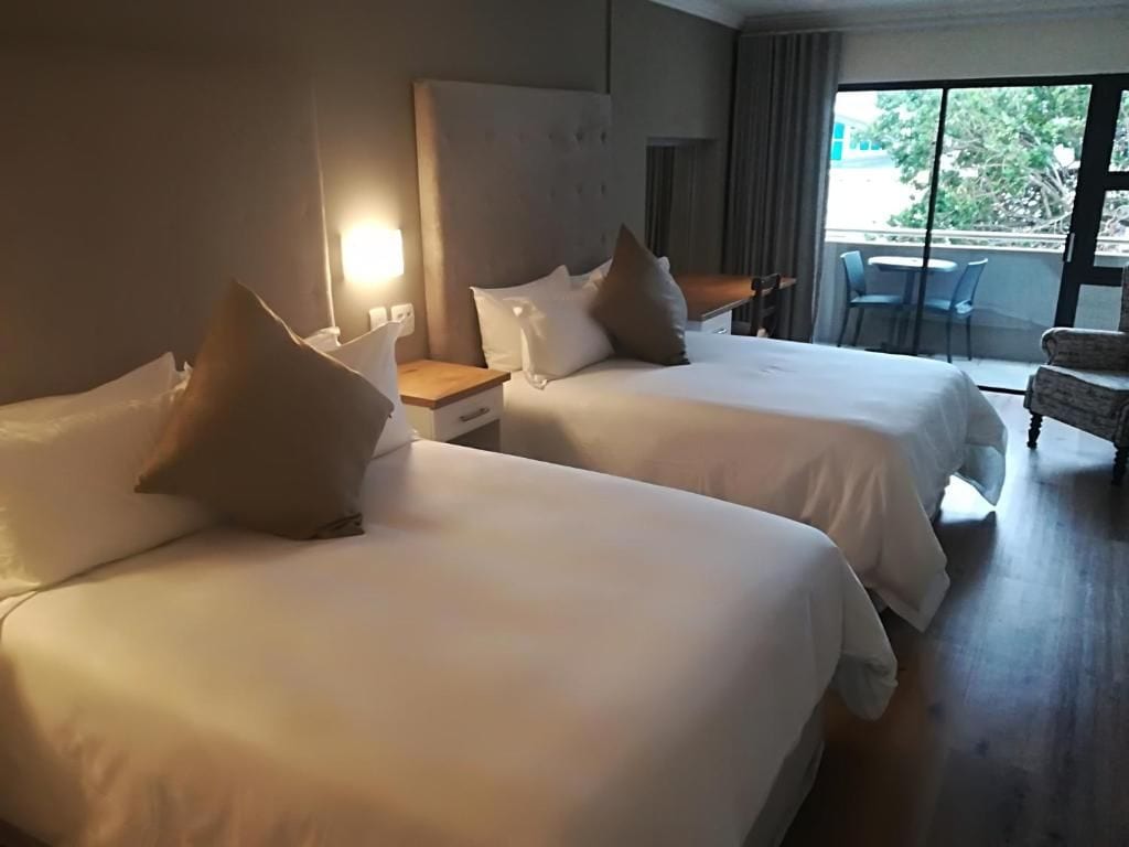 A hotel room with two beds, a desk, and a chair.