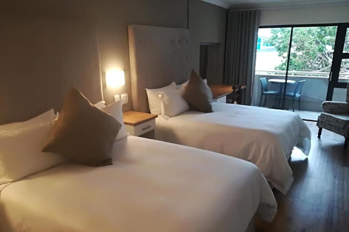 Een hotelkamer met twee bedden, een bureau en een stoel.