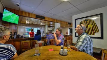 A bar area with wooden furniture, a television screen, and a framed jersey on the wall.