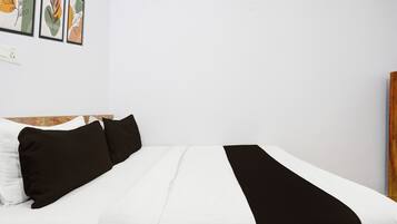 Una cama con ropa de cama blanca y negra, un cabecero de madera y una pared con obras de arte enmarcadas.