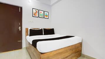 Un dormitorio con cama de madera, ropa de cama blanca y tres cuadros en la pared.