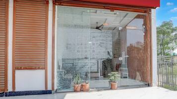 Un edificio moderno con entrada de vidrio, plantas en macetas y un ventilador de techo visible.