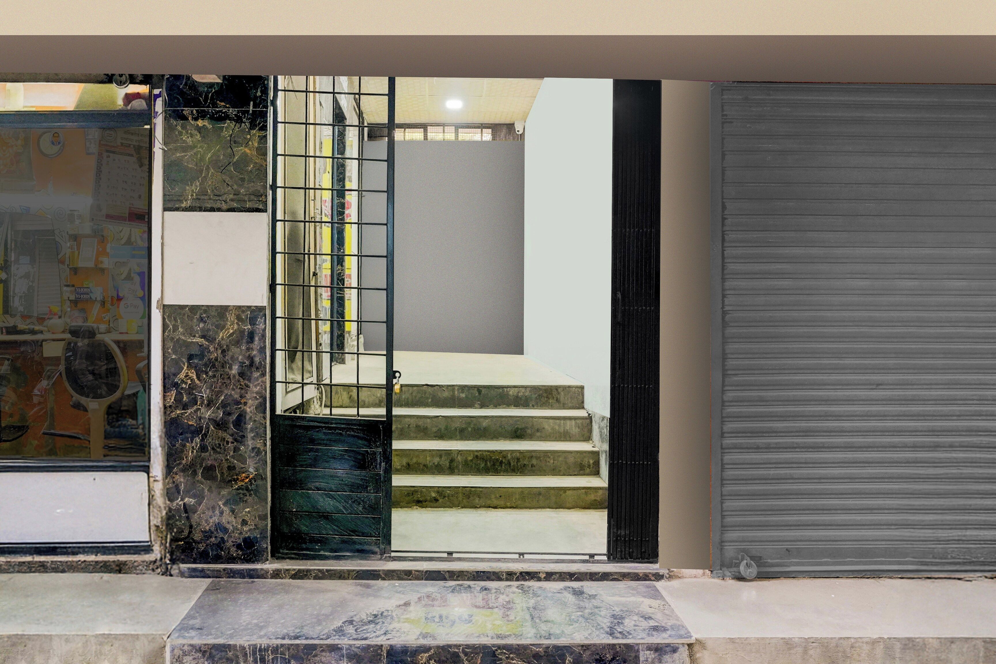 A staircase with a metal gate leading to a room with a closed shutter.
