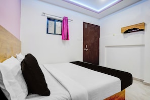 A bedroom with a bed, a window with curtains, a door, and a shelf with items. - Hotel O Nashik Road Railway Station (Nashik)