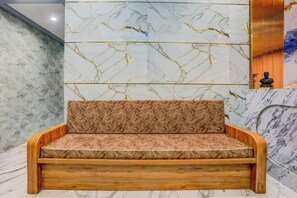A modern interior with a marble wall, a wooden bench, and a statue. - Hotel O Nashik Road Railway Station (Nashik)