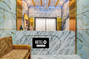 A hotel reception area with a marble reception desk, a sofa, and a ceiling fan. - Hotel O Nashik Road Railway Station (Nashik)
