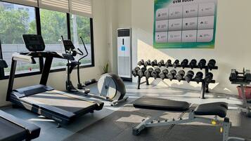 A gym with exercise equipment, including a treadmill, elliptical, and dumbbells.