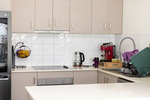 A kitchen with a stove, a coffee maker, and a fruit basket.