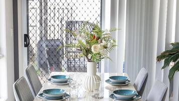 A dining area with a marble table, grey chairs, and a vase with flowers.