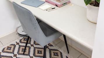 Espacio de trabajo en esquina con escritorio, silla, libros, planta y una caja de madera pequeña.