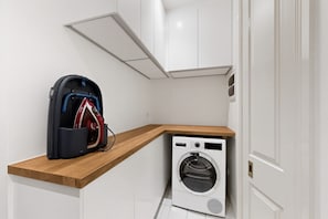 A compact laundry area with a washing machine, a drying rack, and a storage unit. - Spacious 3-bed Apartment in Melbourne CBD (Melbourne)