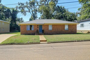 A single-story brick house with a front porch, a small lawn, and a clear sky. - Game Day Base! Steps to Dtwn & Ole Miss Campus (Oxford)