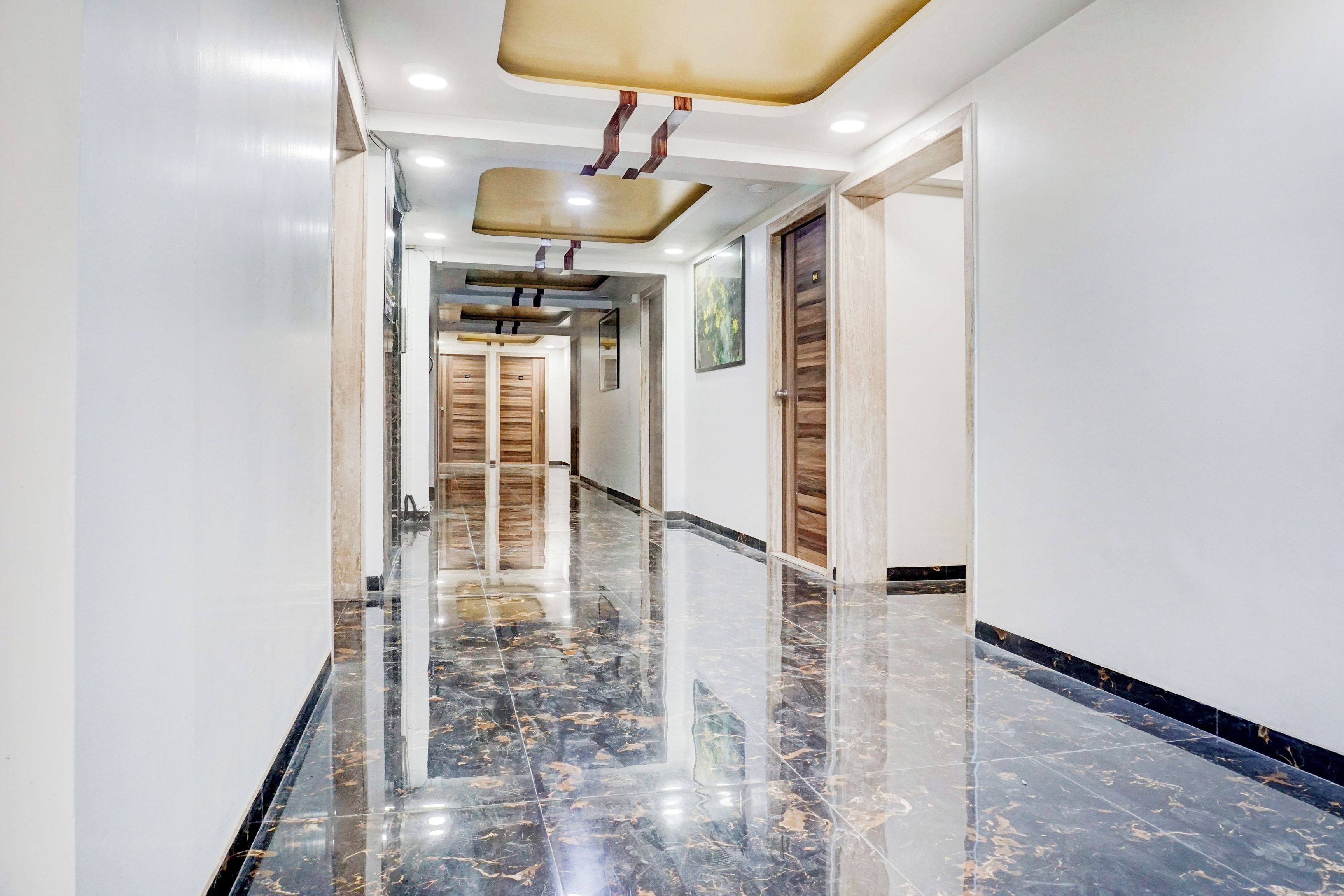 A hallway with a polished marble floor, wooden doors, and recessed lighting.
