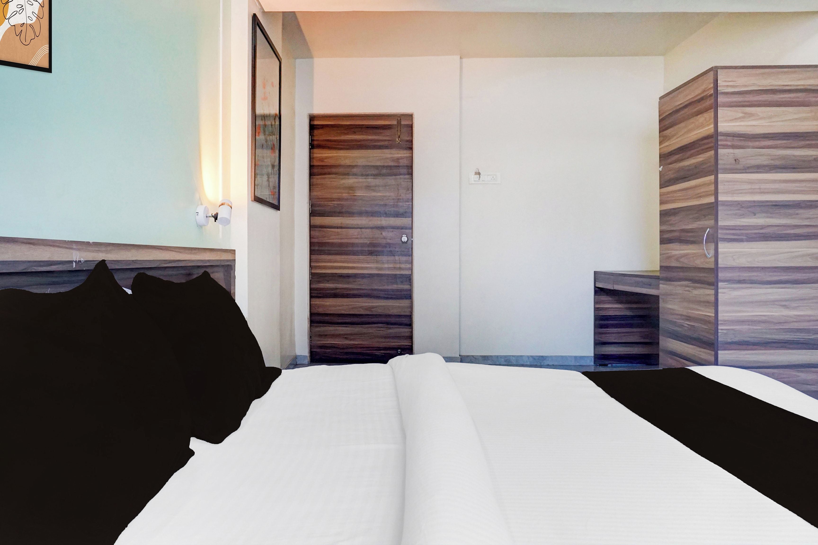 A hotel room with a bed, a wardrobe, and a nightstand.