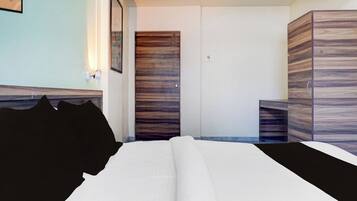 A hotel room with a bed, a wardrobe, and a nightstand.