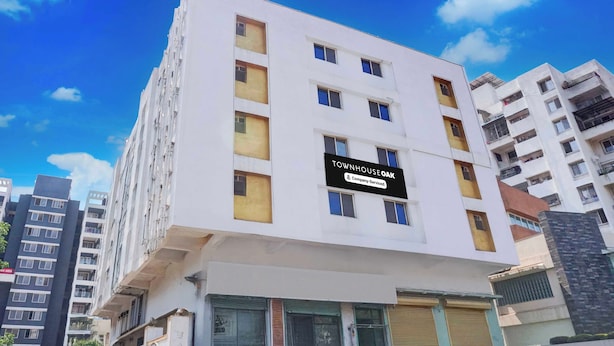 A multi-story building with a sign indicating it is a company-serviced property. - Townhouse Oak Shivsrushti Historical (Pune)