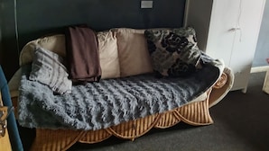 Un divano con una coperta fantasia, un cuscino e un cuscino con motivo a foglia.