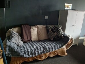 Ein Sofa mit einer gemusterten Decke, einem Kissen und einem Kissen mit Blätermotiv.