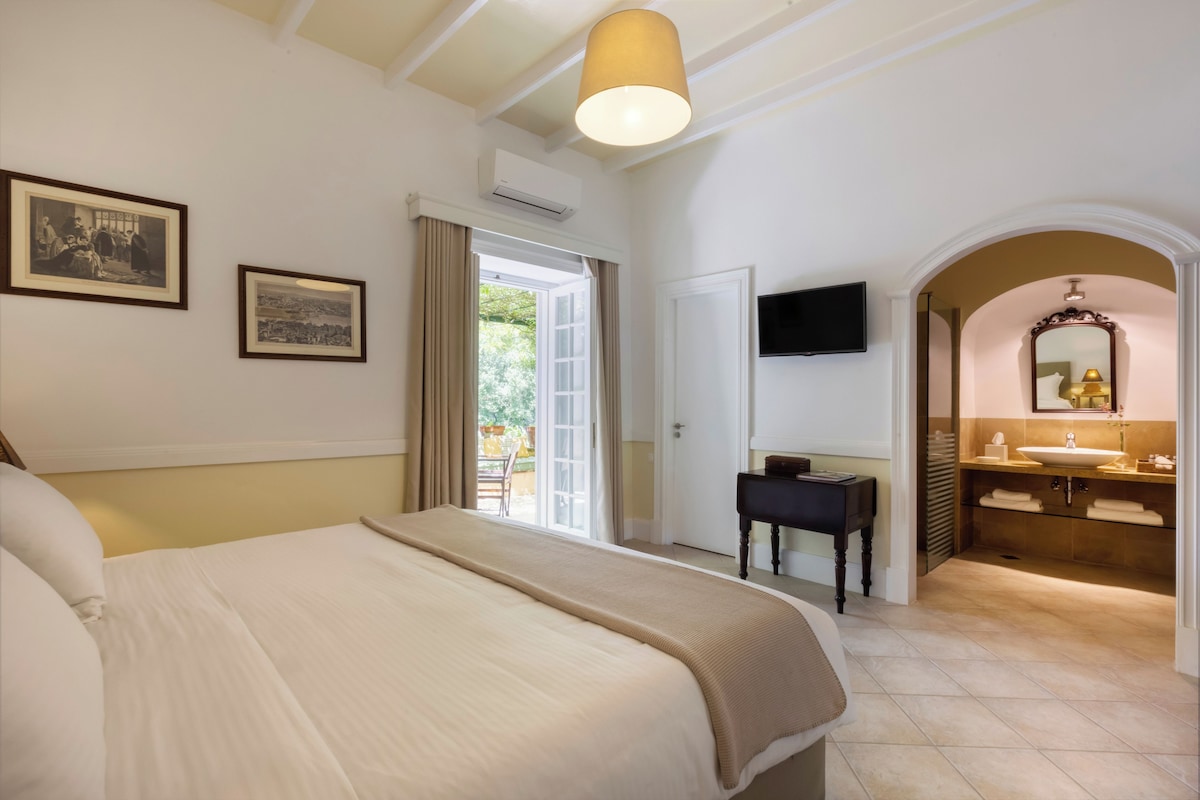 A hotel room with a bed, a desk, a television, and a bathroom with a sink and mirror.