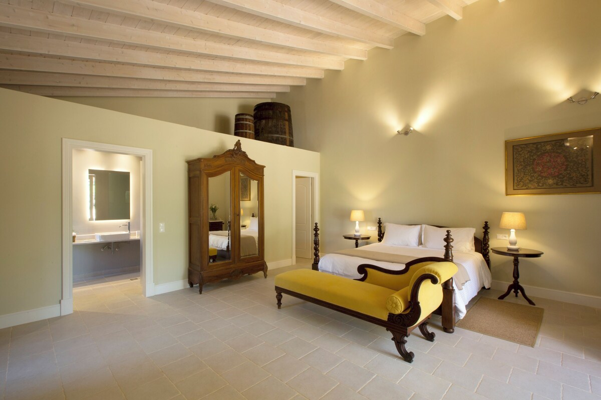A bedroom with a bed, a bench, a mirror, and a dresser.
