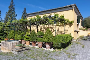 A building with a yellow facade, a gravel courtyard, and potted plants. - PELECAS COUNTRY CLUB (Corfu)