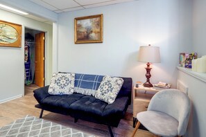 Una sala de estar con un sofá negro, un plaid azul y blanco, una lámpara y una silla.
