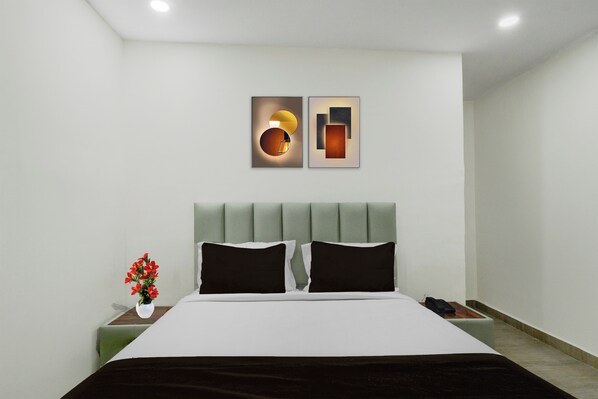A modern bedroom with a bed, two wall-mounted light fixtures, a nightstand, and a vase with flowers. - Townhouse Nagole RTO Office (Hyderabad)