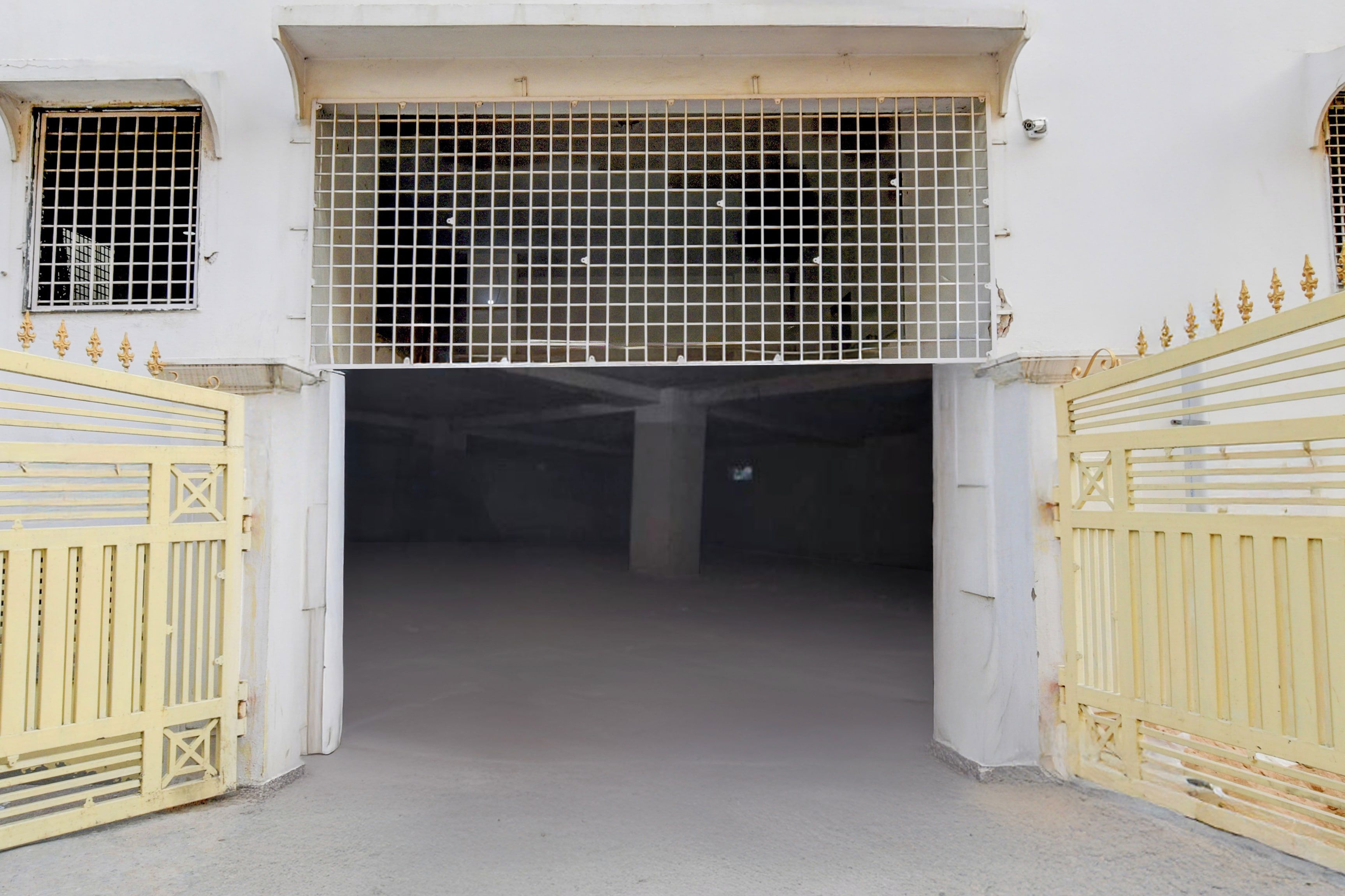Una entrada tancada amb reixa metàl·lica a la porta, un sòl de formigó i una paret blanca.