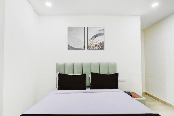 A bedroom with a bed, two pillows, a headboard, and two wall art pieces.
