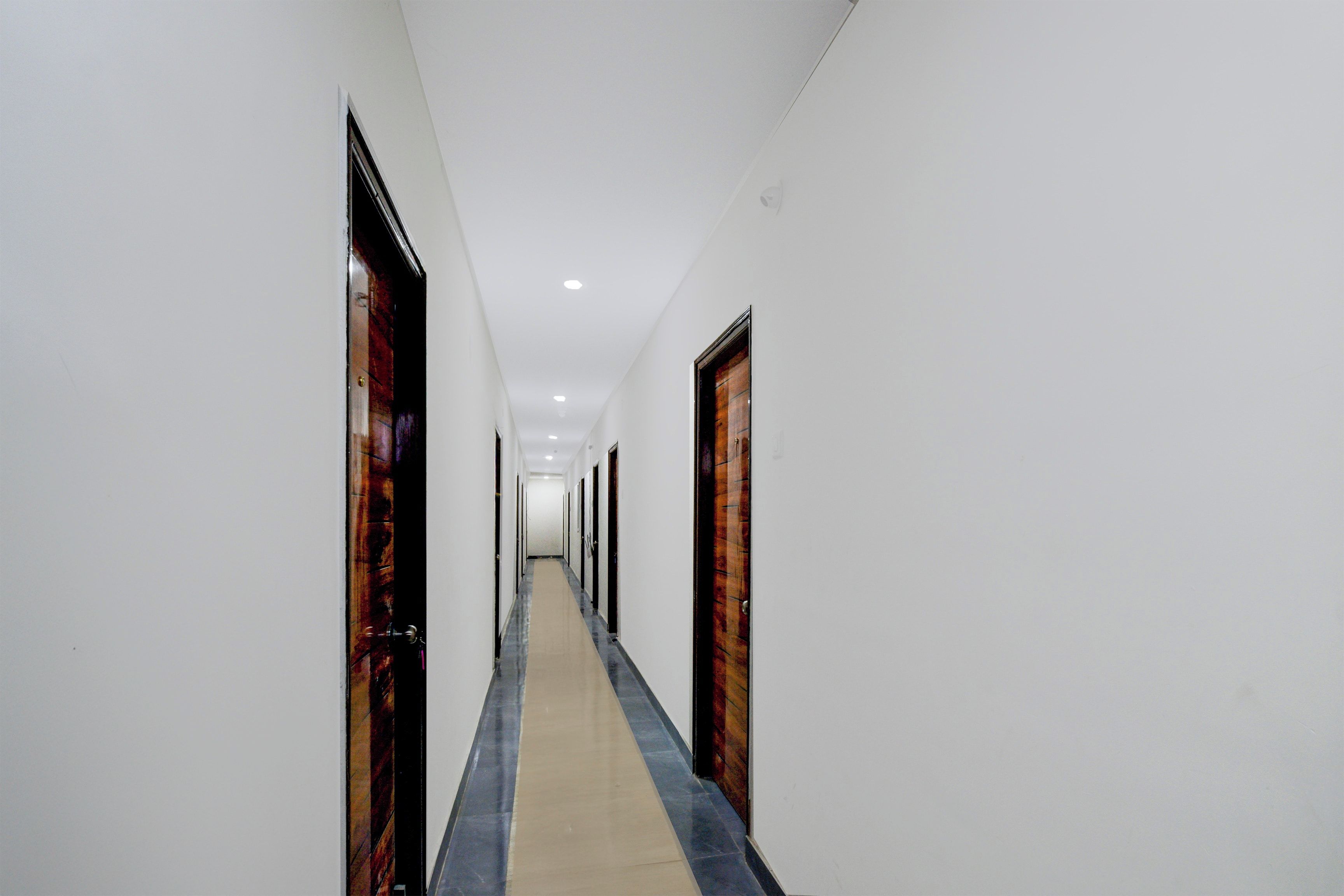 A long, narrow hallway with white walls and doors on both sides.